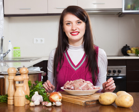 Happy brunette woman  with meat in home kitchenの写真素材