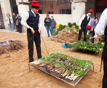 VALLS, SPAIN - JANUARY 26, 2014  Calcotada - popular gastronomical event  Men in traditional peasant dress cooking calsot on open fire  in Vallsのeditorial素材