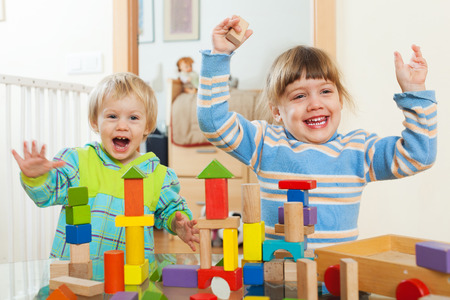 Two happy children playing with wooden blocks  in home interiorの写真素材