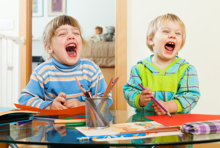 emotional children playing with paper and pencils in home interiorの写真素材