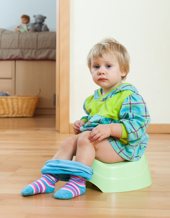 Toddler sitting on green potty in home interiorの写真素材