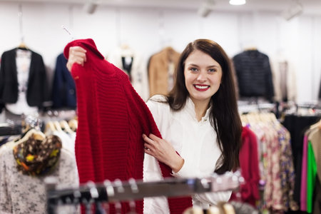 Ordinary woman choosing sweater at clothing store