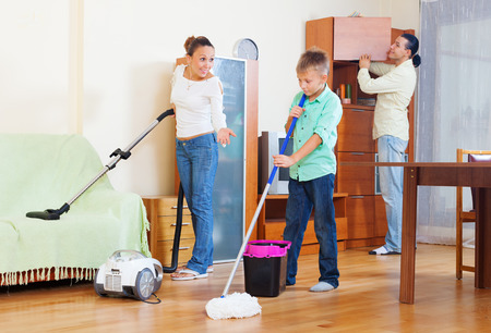 family of three with teenager doing housework with  cleaning equipmentの写真素材