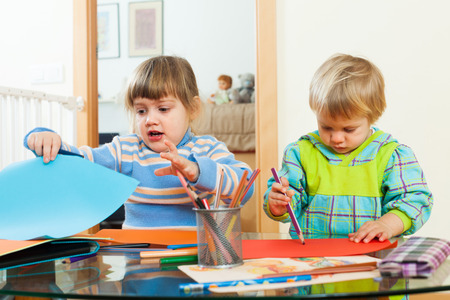 serious children playing with paper and pencils in home interiorの写真素材