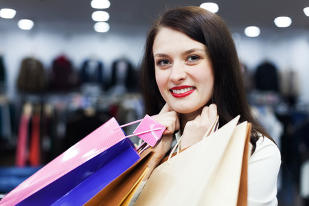 Smiling female buyer with shopping bags at clothing storeの写真素材