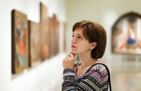 Female visitor looking pictures in art galleryの写真素材