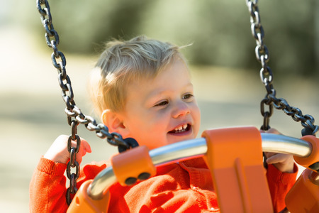 Toddler on swing in summer parkの写真素材