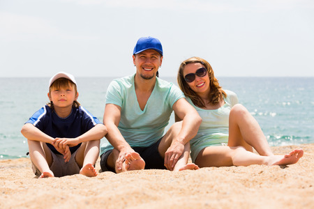 Happy smiling couple with son at sandy beach in summer dayの写真素材
