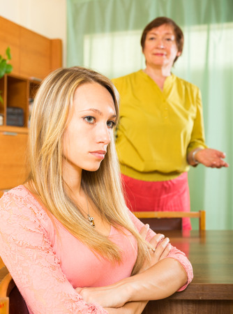adult daughter and mature mother after quarrel at home. Focus on girlの写真素材