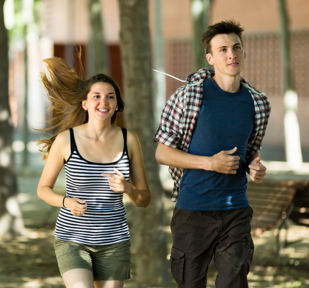 Cheerful young friends jogging on summer morning in the cityの写真素材