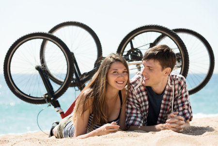 Attractive girl and her boyfriend on beach near bikesの写真素材