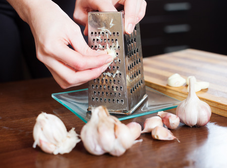 Closeup of  hands  grating garlic with graterの写真素材