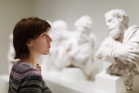 Young woman looking ancient sculptures in art museumの写真素材