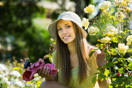 Young casual dressed florist in yard gardening with flowersの写真素材