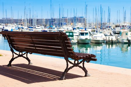  ALICANTE, SPAIN - APRIL 14, 2014: View of Port with yachts from embankment. Alicante. Focus on benchのeditorial素材