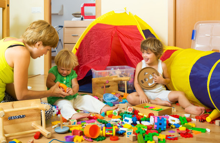 Woman and two children together playing with  toys in  interiorの写真素材