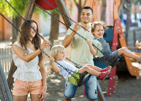 
Excited kids on swings with young parents. Focus on womanの写真素材