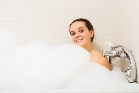 Happy young woman covered foam in bathの写真素材