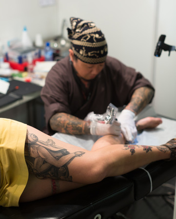 BARCELONA, SPAIN - OCTOBER 3, 2014: Professional artist  doing colorful tattoo on  client leg. The 17th edition of The Barcelona Tattoo Expoのeditorial素材