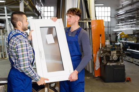 adults working in uniform examining a window at workshopの写真素材