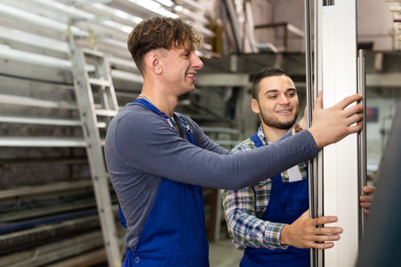 Two workers choosing PVC window profile at stand in storageの写真素材