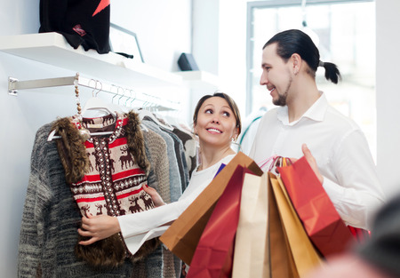 happy couple choosing jacket at clothing shopの写真素材