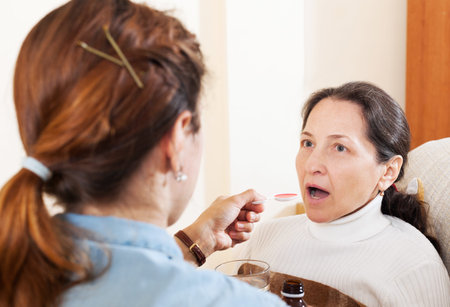 Adult woman caring for illness senior mother at home.の写真素材