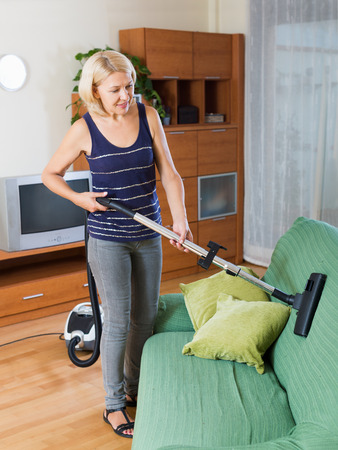 Photo of adult woman diligently cleaning living roomの写真素材
