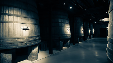 Aged photo of vertical large wooden barrels in old cellarの写真素材