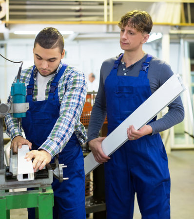 Two careful young men working on a machine in toolroom