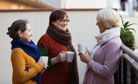Group of smiling female pensioners drinking tea at balconyの写真素材