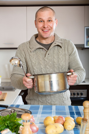 Portrait of happy smiling man cooking at home kitchenの写真素材
