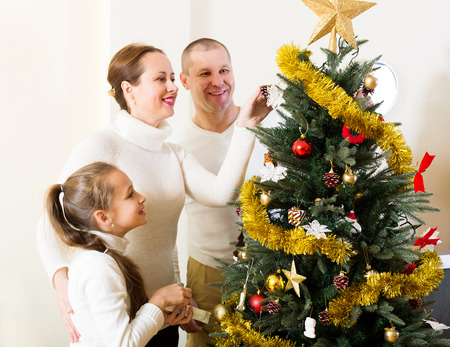 Happy parents and child preparing for Christmas at home. Focus on womanの写真素材