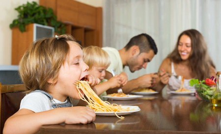 Positive family of four having lunch with spaghetti at homeの写真素材