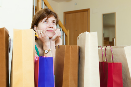 Beautiful smiling young woman at home with shopping bagsの写真素材