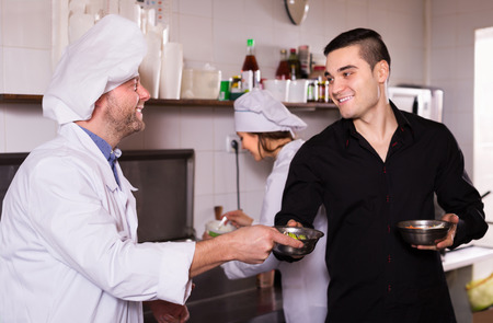 Smiling chefs and waiter working at eating house. Focus on chefs manの写真素材