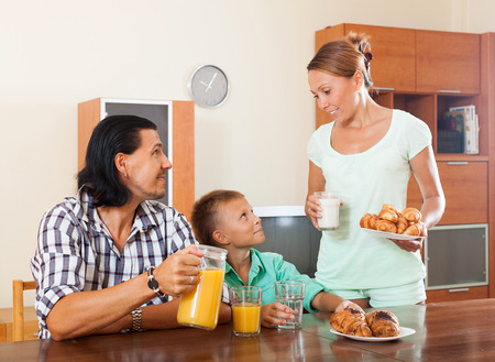 parents and teenager eating breakfast in home interiorの写真素材