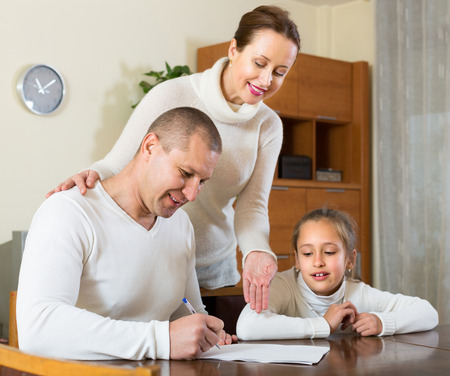 Smiling father with cheerful daughter complete a questionnaire for the social worker at homeの写真素材