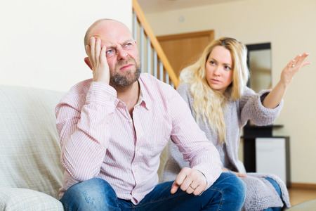 Angry guy and woman during quarrel in living room at homeの写真素材