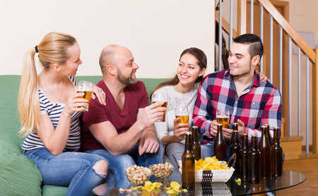 Cheerful smiling young adults drinking beer at home. Focus on manの写真素材