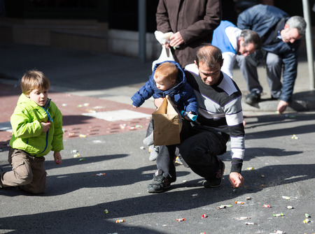 BARCELONA, SPAIN - MARCH 3, 2015: Closeup of people collecting caramels from asphalt. Sant Medir - event, during which participants were given tons of caramelsのeditorial素材