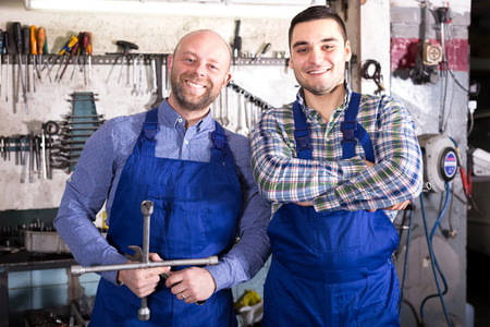 Portrait of two happy repairmen with tools at a workshopの写真素材