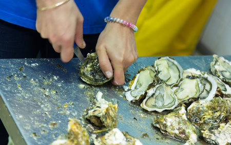 Close-up of worker opening oysters at restaurant