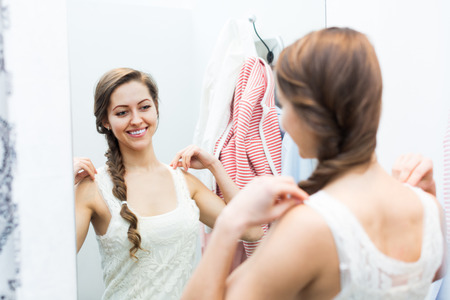 Beautiful smiling girl standing at boutique changing cubicleの写真素材