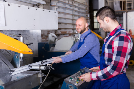 Couple of 30 years old workers near milling machine at factoryの写真素材