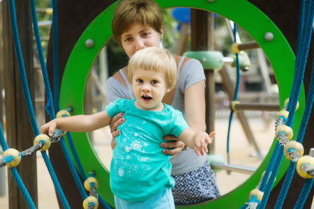 Baby girl with mother at   playground in summerの写真素材