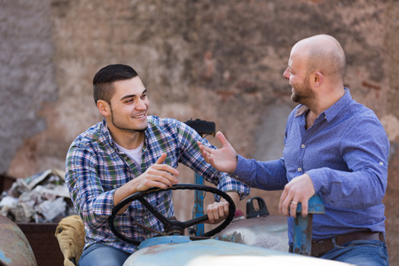 Two happy american mechanics reparing old agrimotors at farmの写真素材