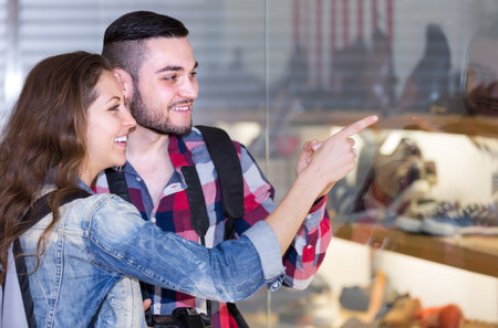 Young happy adults with photocamera  looking at shopwindowsの写真素材