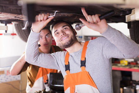 Professional positive young mechanics repairing car of clientの写真素材