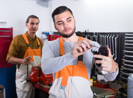 Two serious professional workmen in uniform at workshop. Selective focus